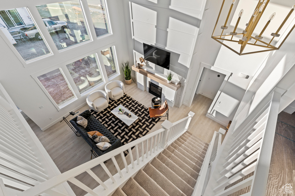 Living room with wood finished floors, a fireplace with flush hearth, plenty of natural light, and a high ceiling