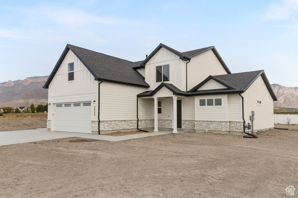 Modern farmhouse style home featuring board and batten siding, driveway, and stone siding