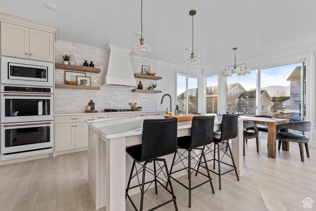 Kitchen with open shelves, gas cooktop, double oven, light countertops, and built in microwave