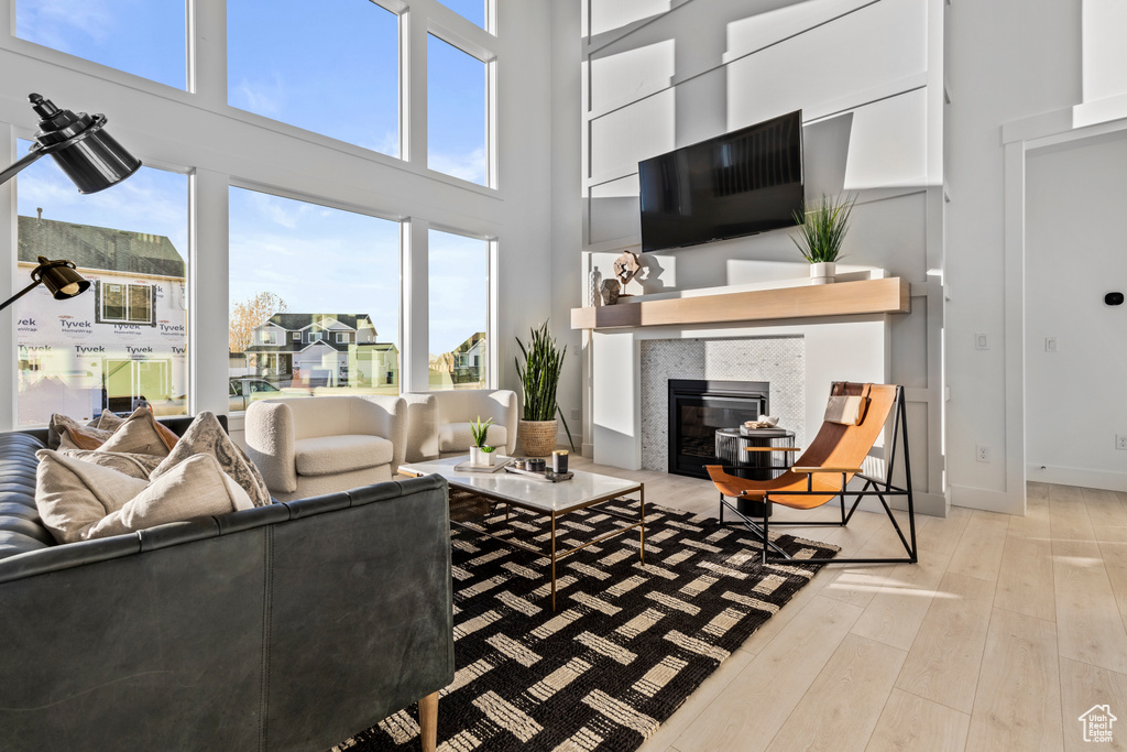 Living area featuring a towering ceiling, wood finished floors, and a tile fireplace