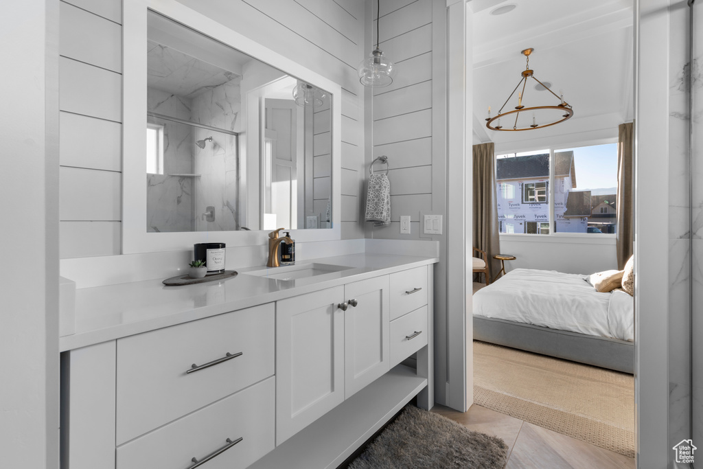 Full bathroom featuring vanity, ensuite bathroom, tile patterned floors, a chandelier, and a marble finish shower