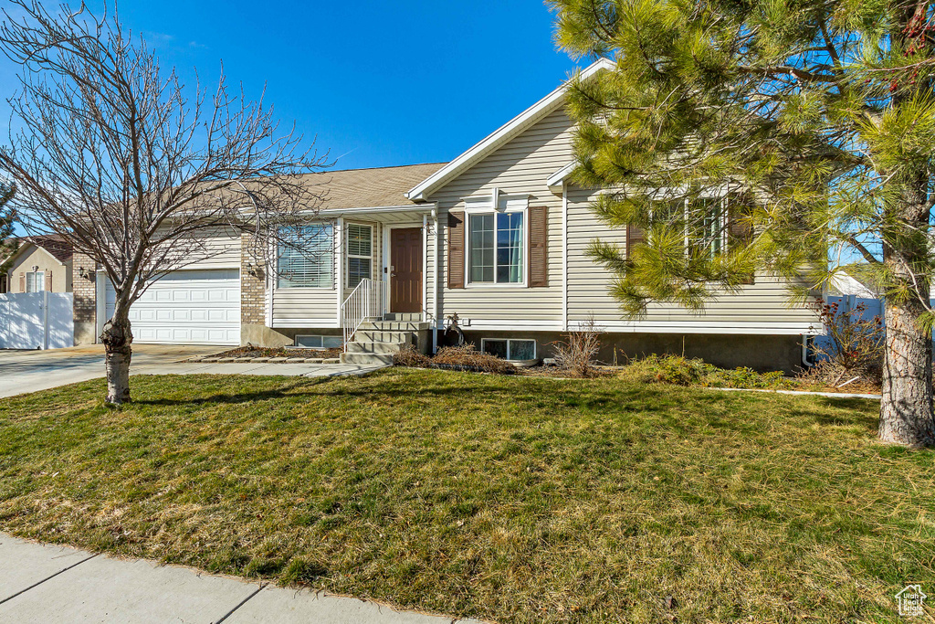 Single story home with an attached garage, entry steps, a front yard, and concrete driveway