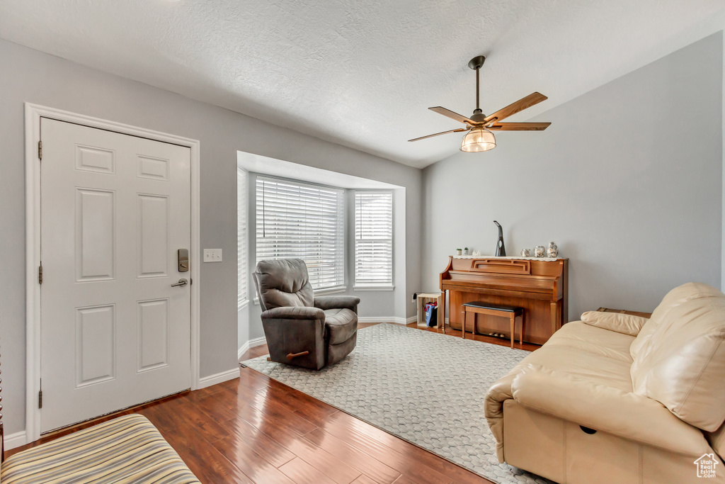 Living room featuring baseboards, a textured ceiling, ceiling fan, and wood finished floors