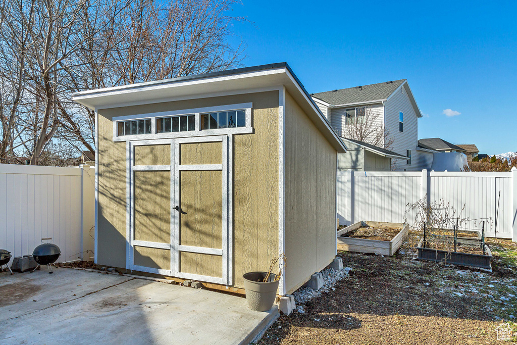 View of shed with a fenced backyard and a vegetable garden