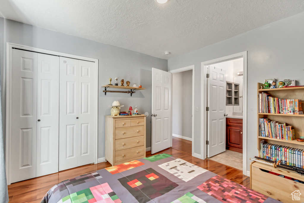 Bedroom featuring baseboards, a closet, light wood finished floors, and a textured ceiling