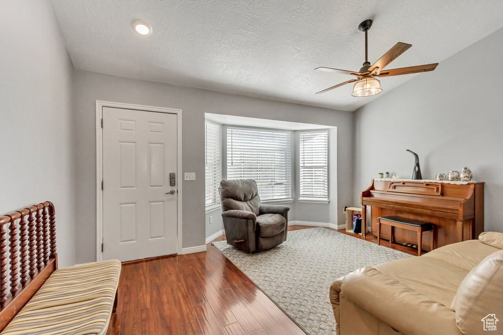Living room with baseboards, a ceiling fan, dark wood finished floors, and a textured ceiling