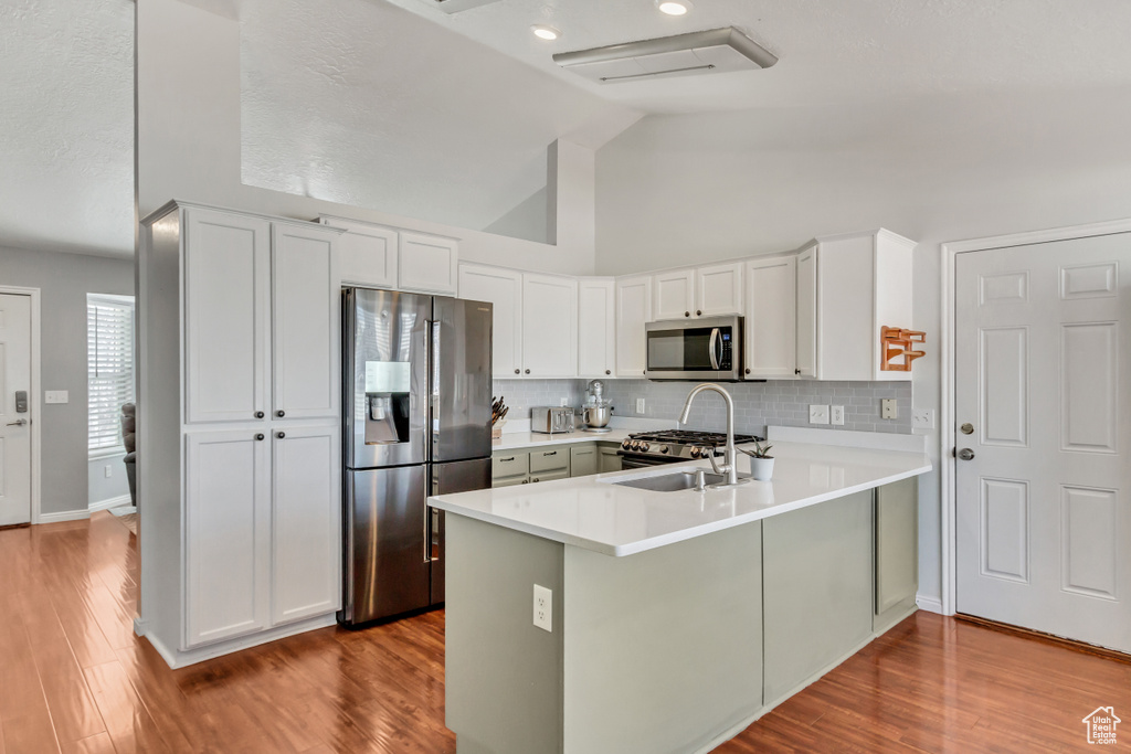 Kitchen with a sink, appliances with stainless steel finishes, a peninsula, and light countertops