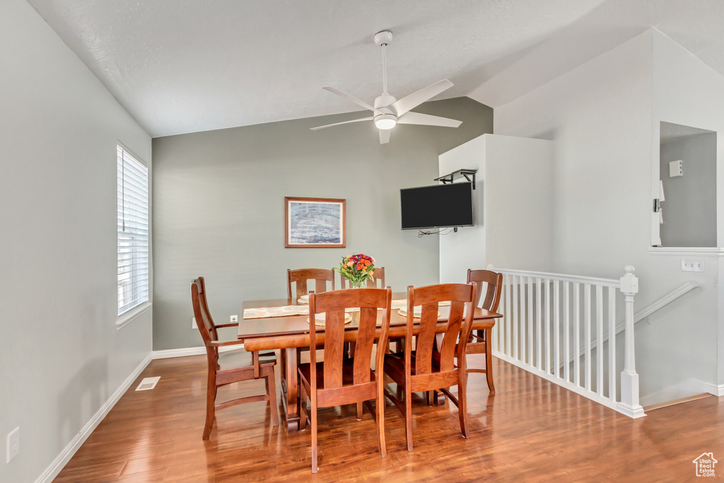 Dining area featuring a ceiling fan, baseboards, wood finished floors, and lofted ceiling