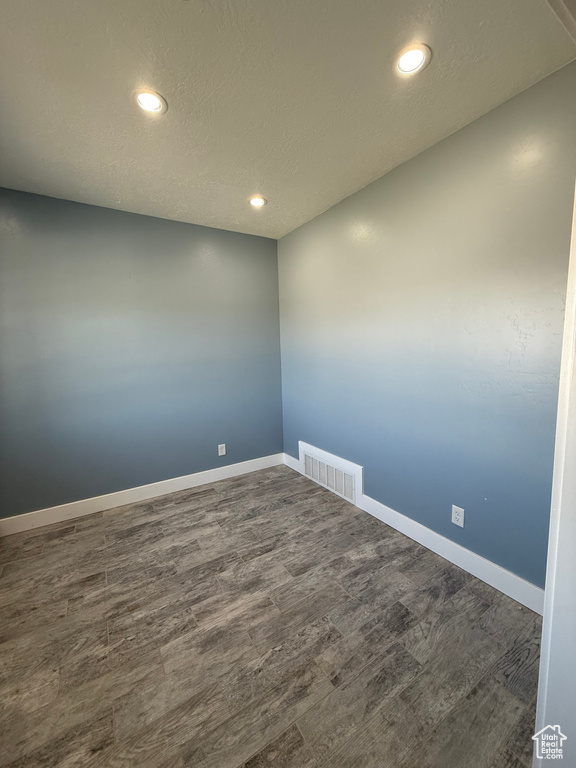 Empty room featuring a textured ceiling, recessed lighting, baseboards, visible vents, and dark wood-style floors