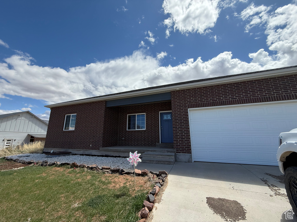 Single story home with an attached garage, driveway, and brick siding
