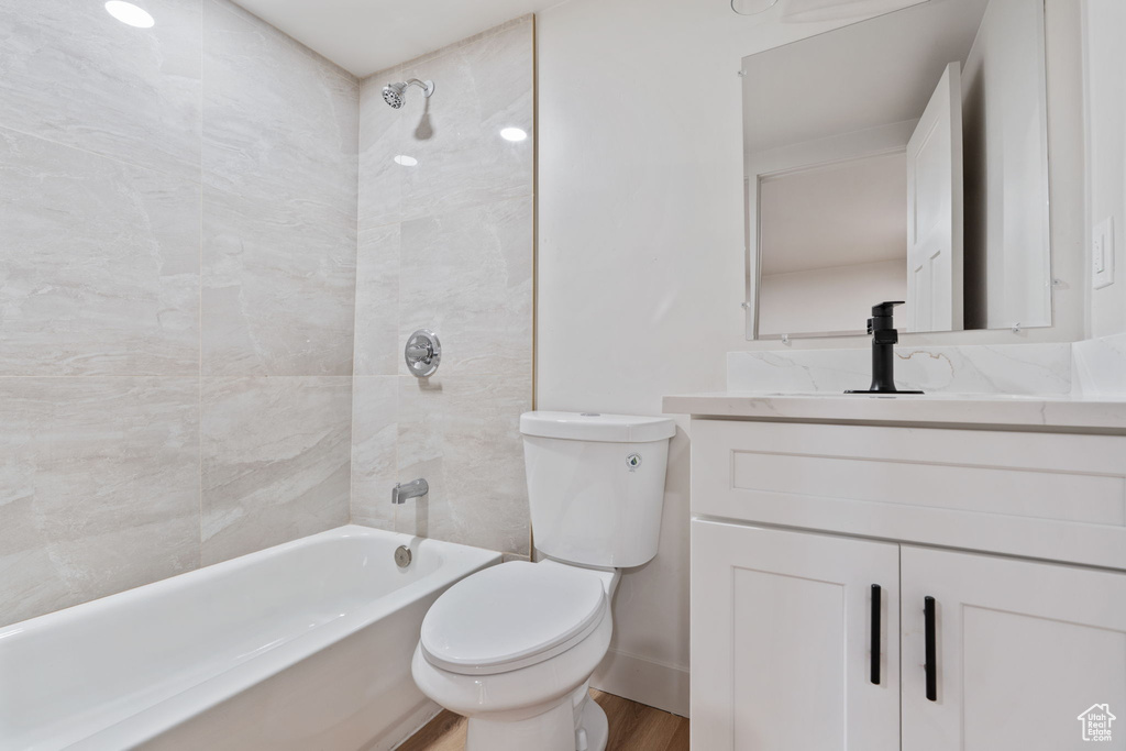 Bathroom with vanity, wood finished floors, toilet, baseboards, and shower / washtub combination