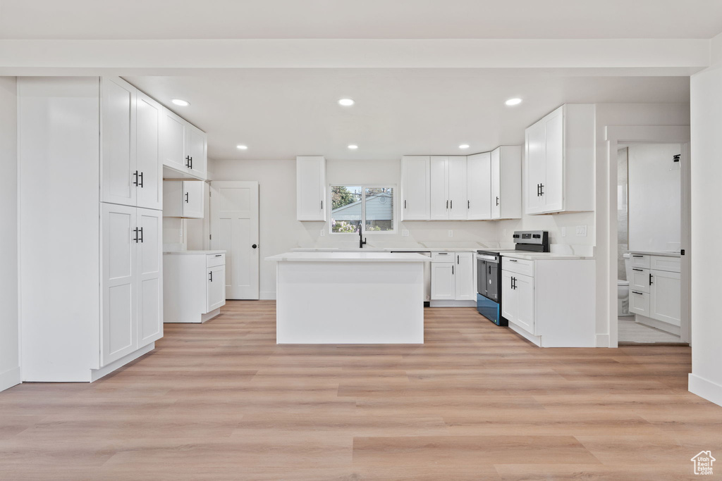 Kitchen with a kitchen island, light wood-type flooring, white cabinets, stainless steel appliances, and recessed lighting
