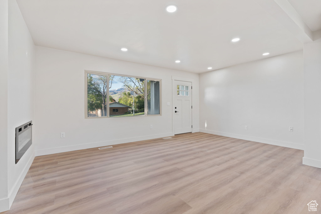 Unfurnished living room featuring recessed lighting, light wood-style flooring, heating unit, and baseboards