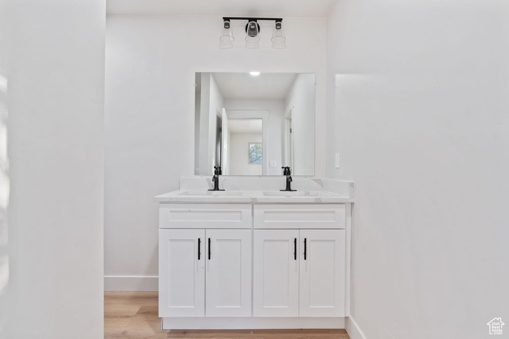 Bathroom featuring a sink, baseboards, double vanity, and wood finished floors