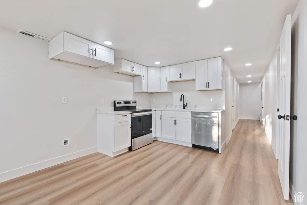 Kitchen with stainless steel appliances, baseboards, a sink, and light wood-style floors