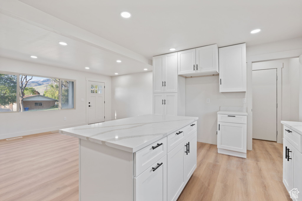 Kitchen with light wood-style floors, light stone countertops, recessed lighting, and white cabinetry