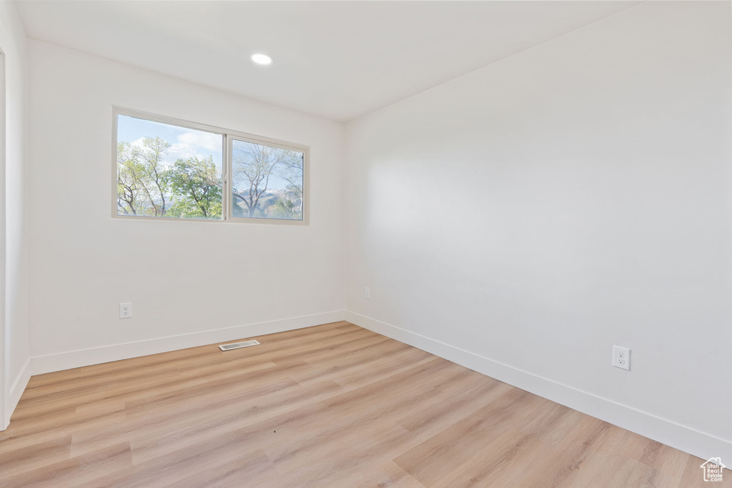 Unfurnished room with visible vents, light wood-style flooring, baseboards, and recessed lighting