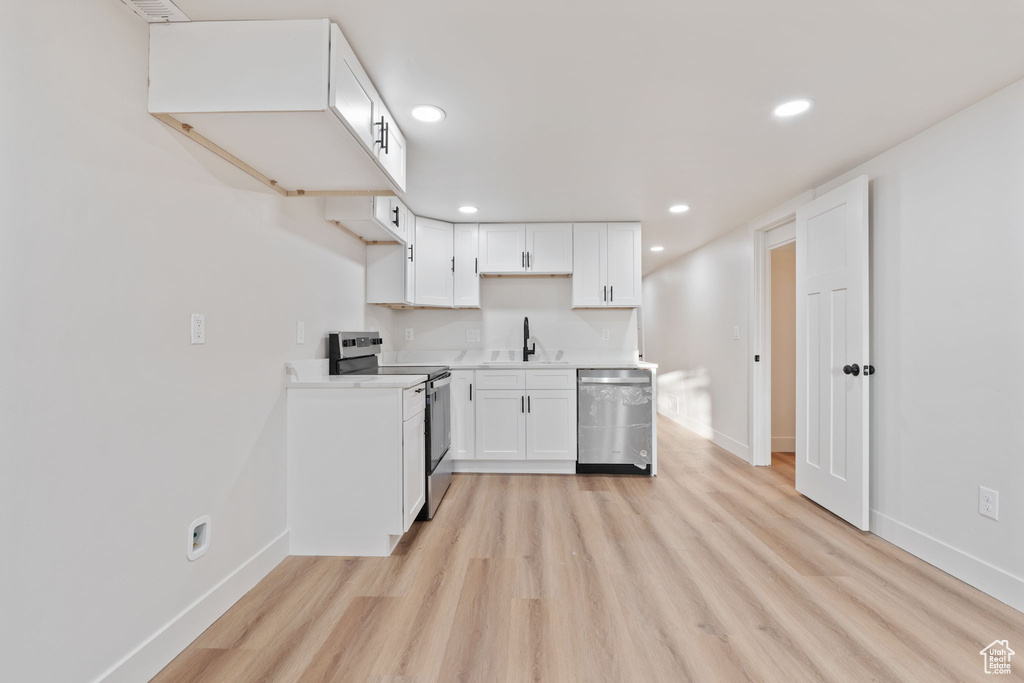 Kitchen with a sink, baseboards, stainless steel appliances, and light wood-style flooring