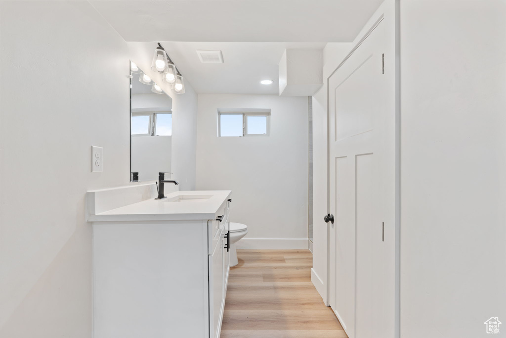 Bathroom featuring visible vents, wood finished floors, vanity, baseboards, and toilet