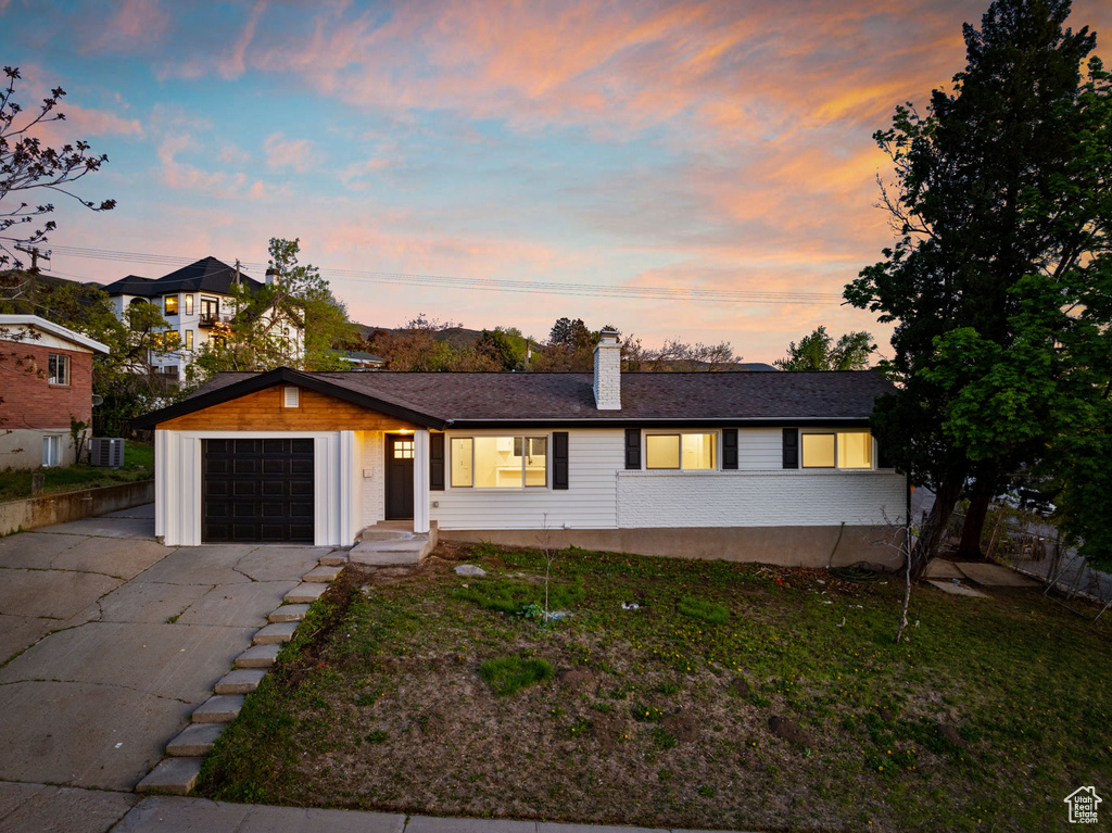 Ranch-style home with cooling unit, an attached garage, concrete driveway, and a chimney
