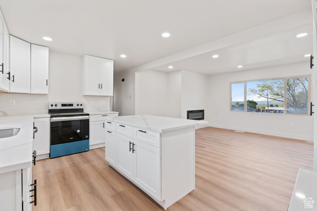 Kitchen with electric range, recessed lighting, a center island, white cabinets, and light wood finished floors