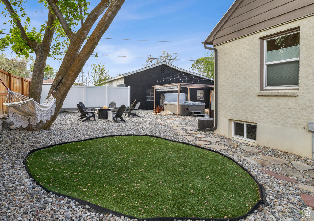 View of yard featuring fence private yard, a hot tub, an outdoor fire pit, and a patio