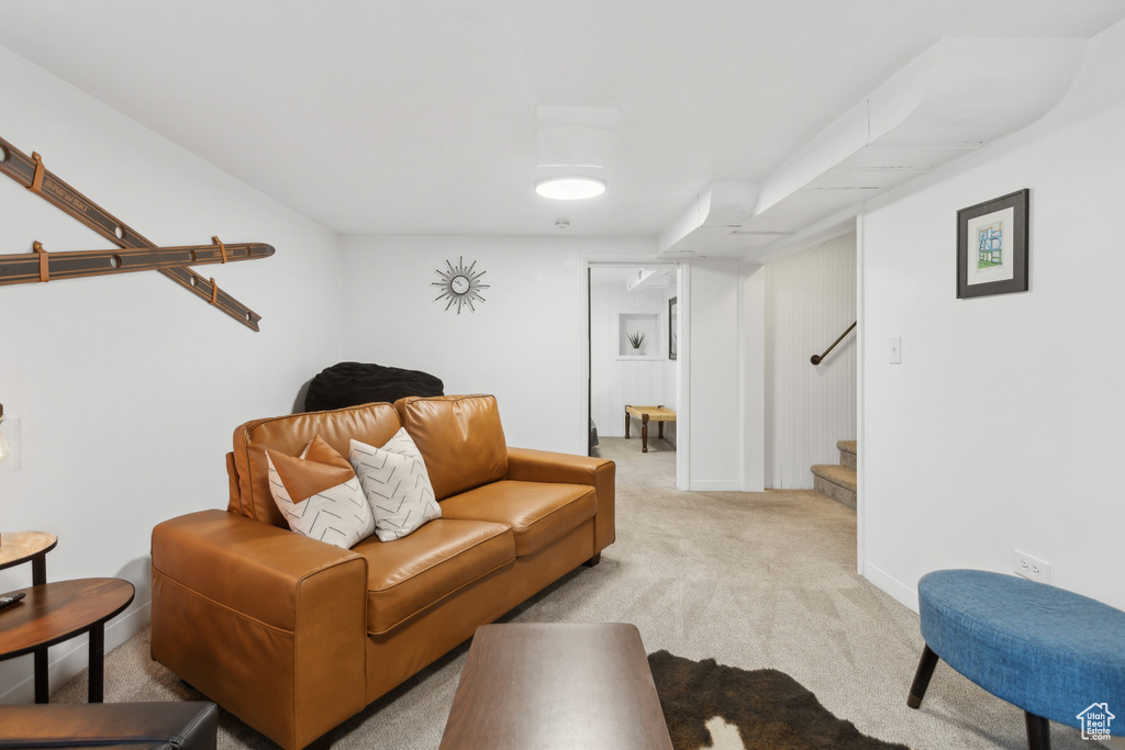 Living area featuring baseboards, light colored carpet, and stairway