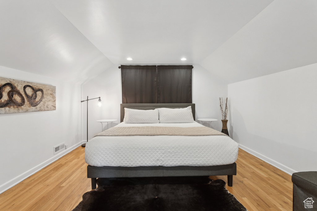 Bedroom featuring baseboards, visible vents, light wood-style flooring, and lofted ceiling