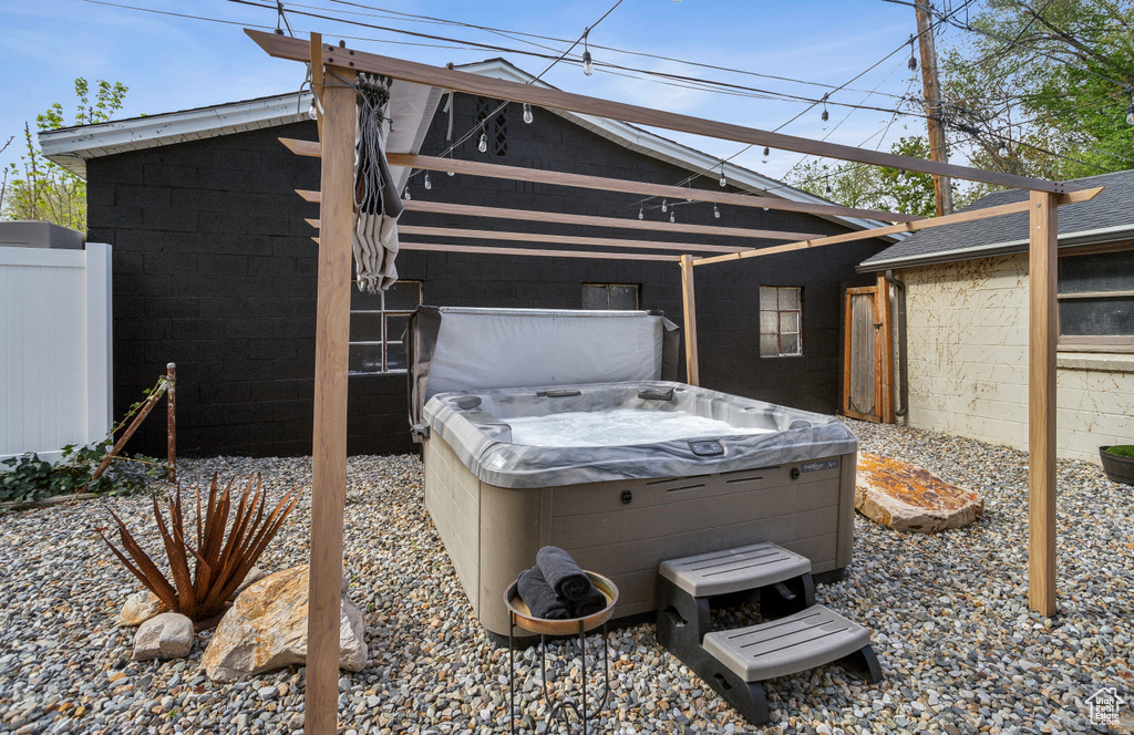 View of side of home with concrete block siding, a hot tub, and fence