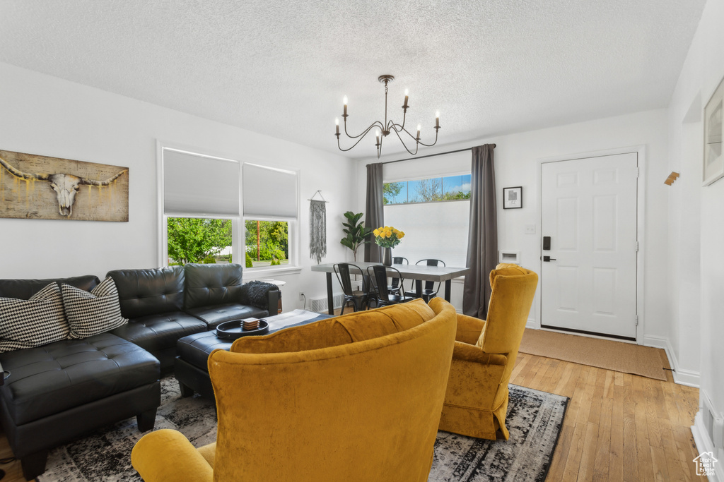 Living area featuring an inviting chandelier, a textured ceiling, baseboards, and hardwood / wood-style floors