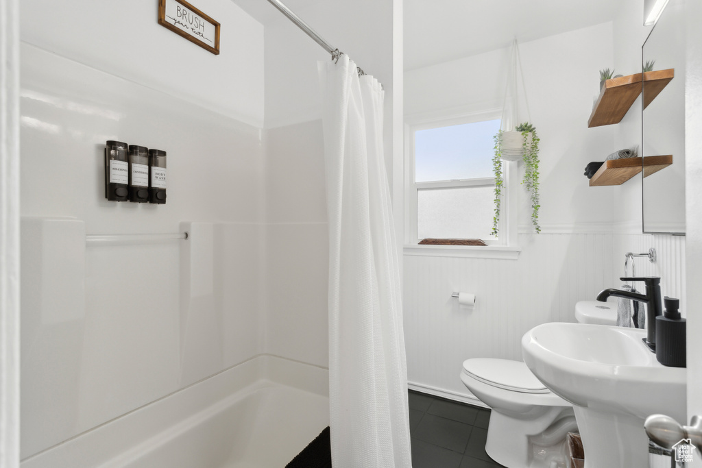 Full bathroom featuring tile patterned floors, a wainscoted wall, a shower with curtain, and toilet