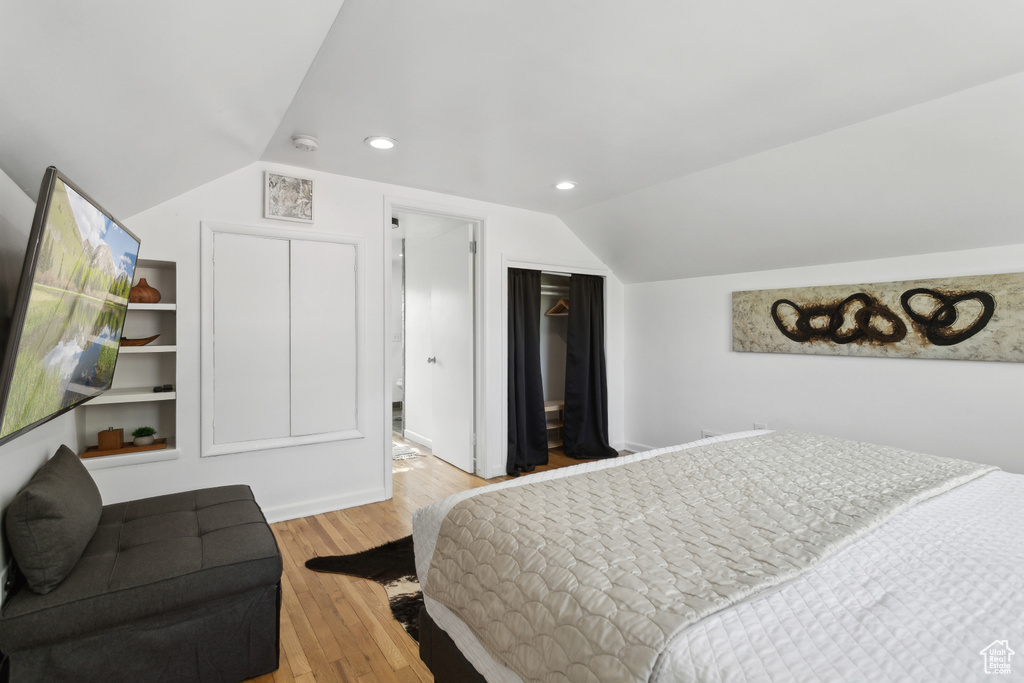 Bedroom with a closet, recessed lighting, wood finished floors, and lofted ceiling