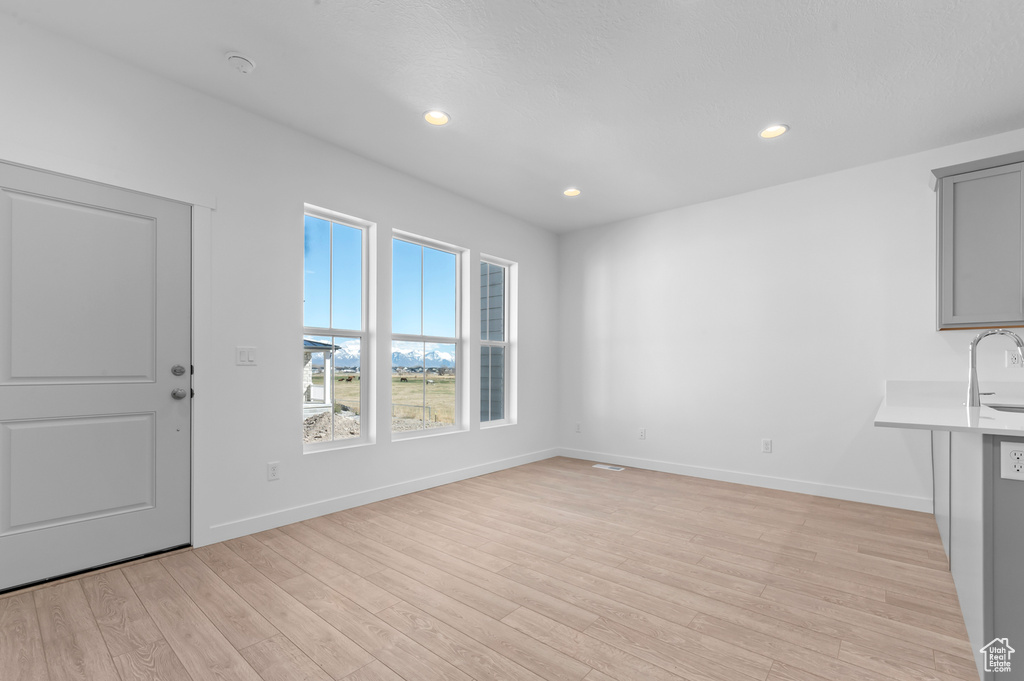 Unfurnished living room with baseboards, a sink, light wood finished floors, and recessed lighting