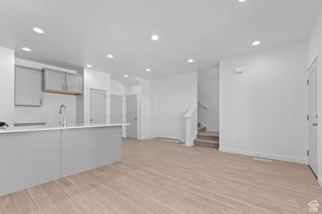 Kitchen featuring gray cabinetry, light countertops, a sink, light wood-style floors, and recessed lighting