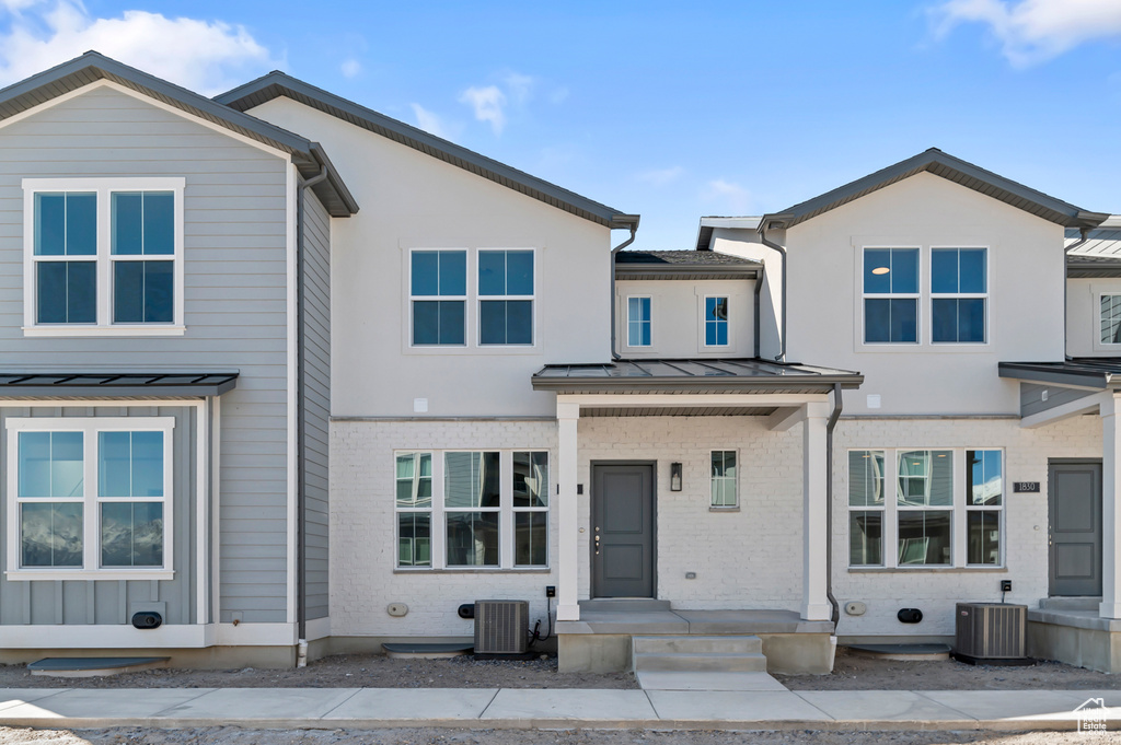 View of front facade with brick siding, central AC, a standing seam roof, and metal roof
