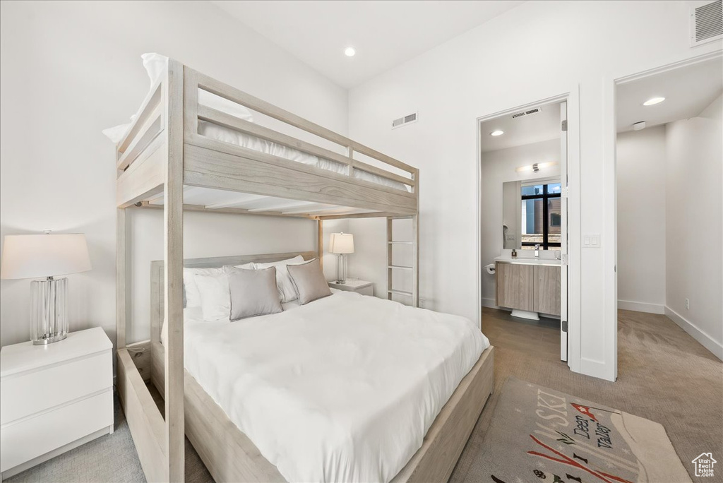 Carpeted bedroom with recessed lighting, visible vents, and ensuite bathroom