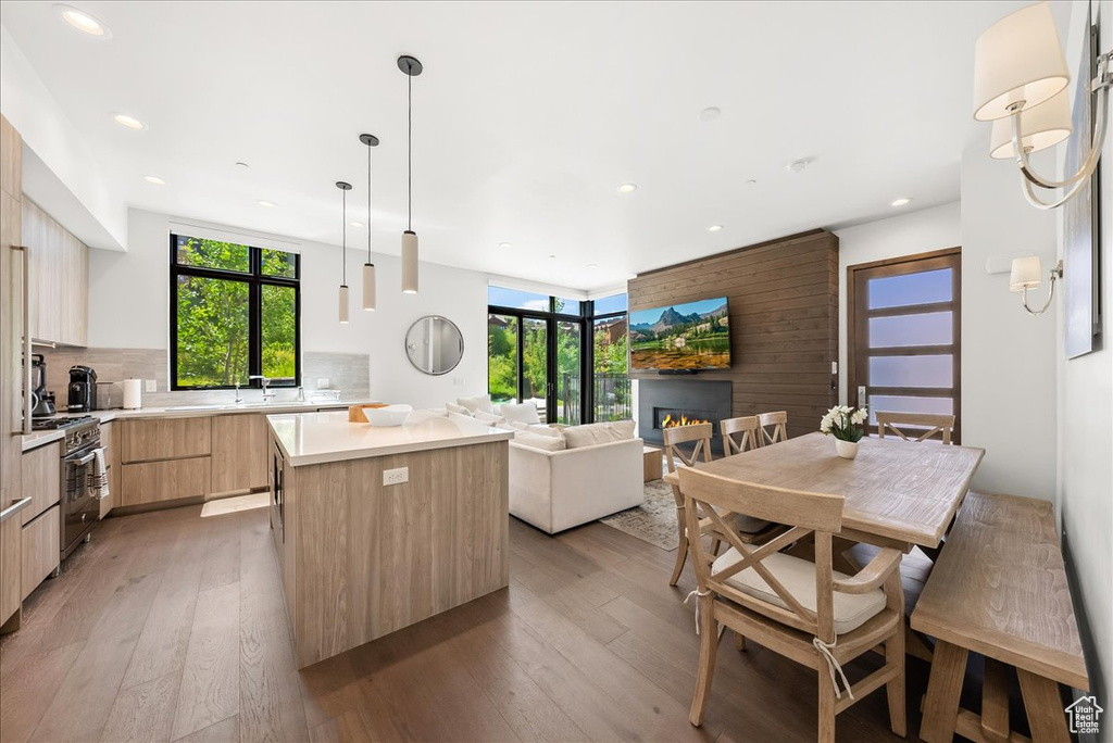 Kitchen with light brown cabinetry, high end stainless steel range, light wood-style floors, modern cabinets, and a center island