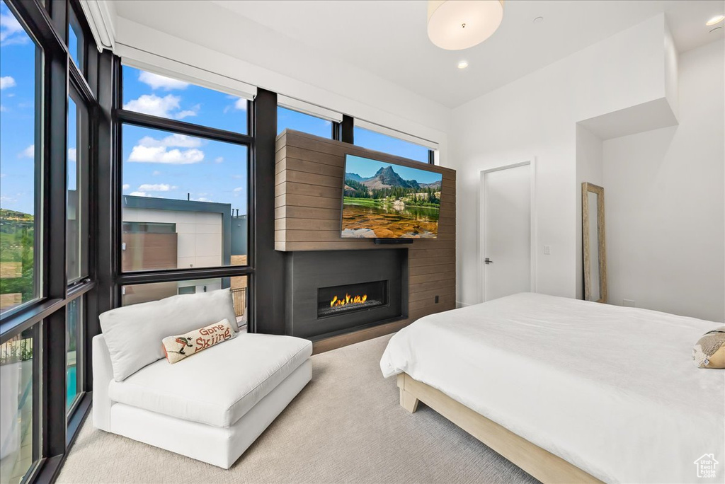 Carpeted bedroom with recessed lighting and a glass covered fireplace