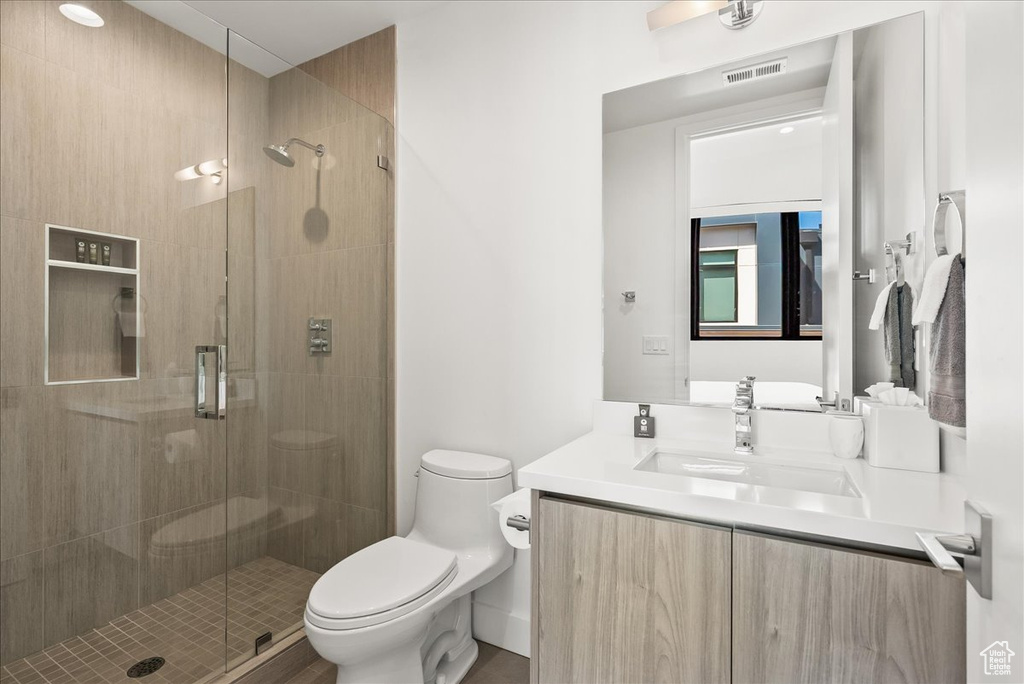 Bathroom with vanity, a stall shower, toilet, and visible vents