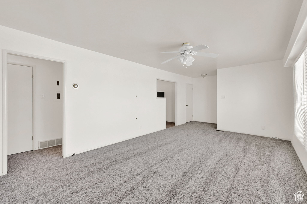 Empty room featuring visible vents, a ceiling fan, and carpet flooring