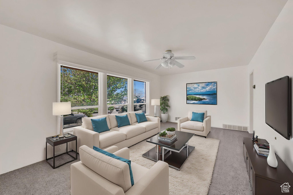 Carpeted living area featuring a ceiling fan and visible vents