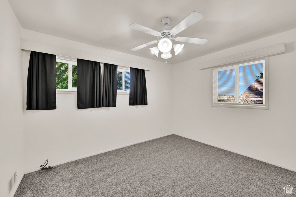Carpeted spare room featuring baseboards, a ceiling fan, and visible vents