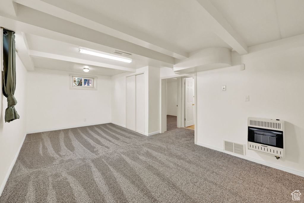 Basement with heating unit, baseboards, carpet flooring, and visible vents