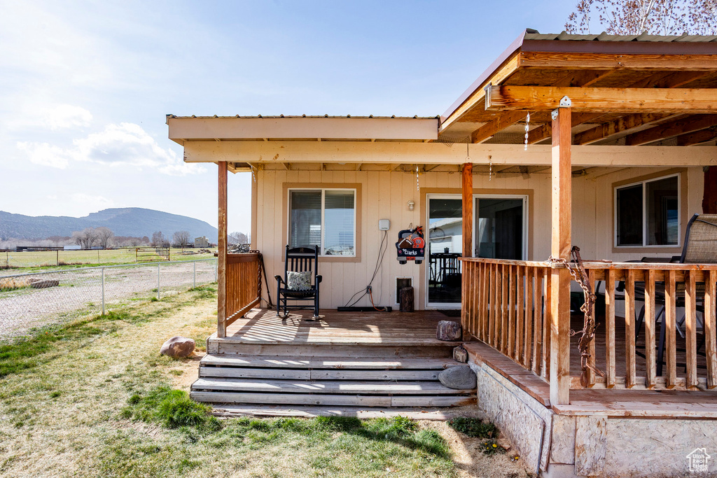 Back of house featuring a deck with mountain view, metal roof, and fence
