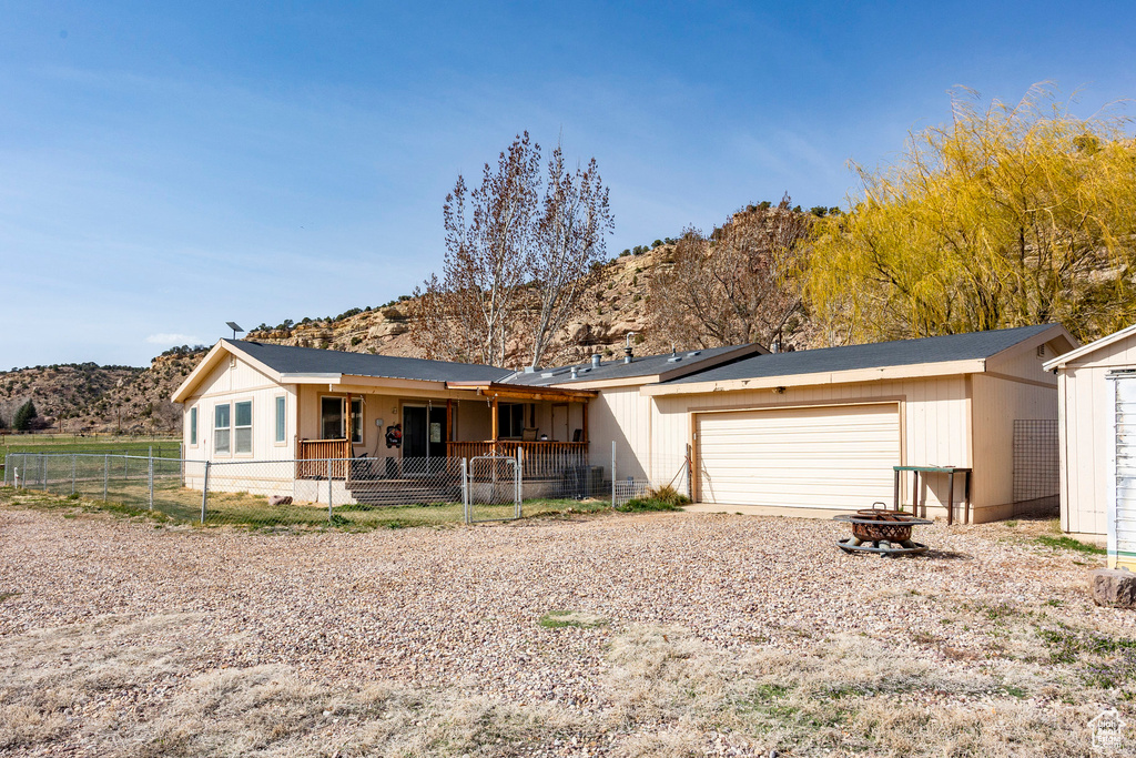 View of front facade featuring driveway, fence private yard, a garage, a mountain view, and an outdoor fire pit