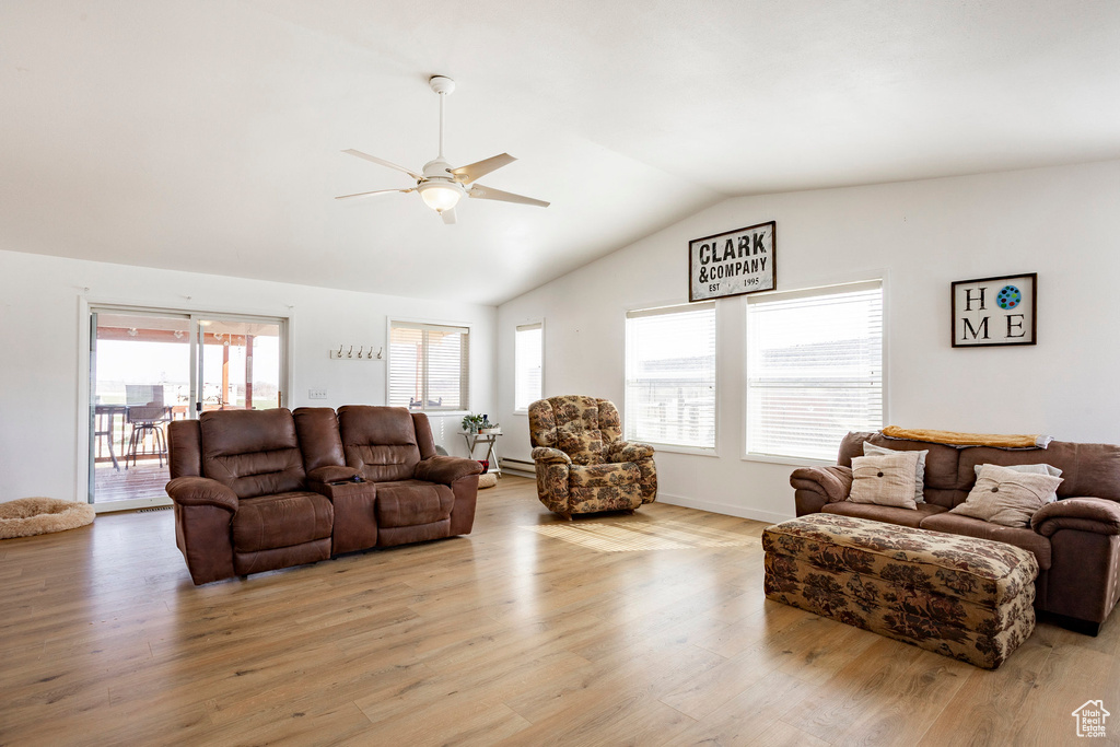Living room with light wood finished floors, ceiling fan, and lofted ceiling