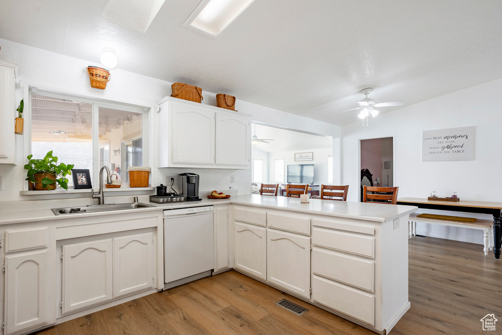 Kitchen with a ceiling fan, light wood-type flooring, dishwasher, a sink, and a peninsula