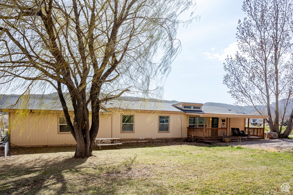 Rear view of property with a lawn and a deck