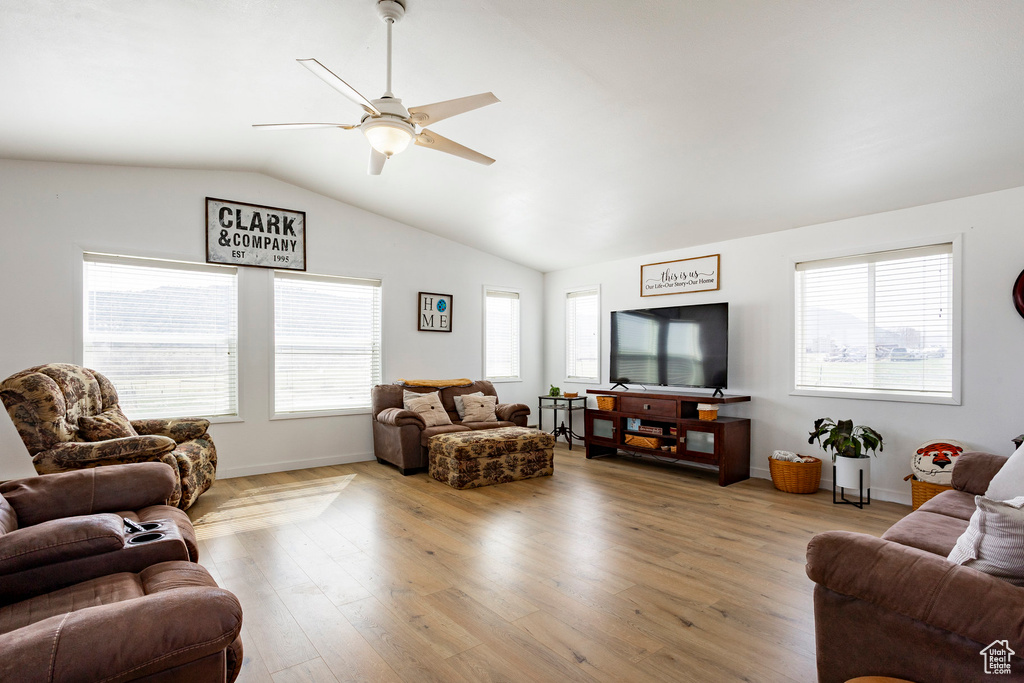 Living area with light wood-style floors, a ceiling fan, baseboards, and vaulted ceiling