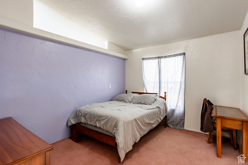 Bedroom featuring a textured ceiling, light colored carpet, and lofted ceiling